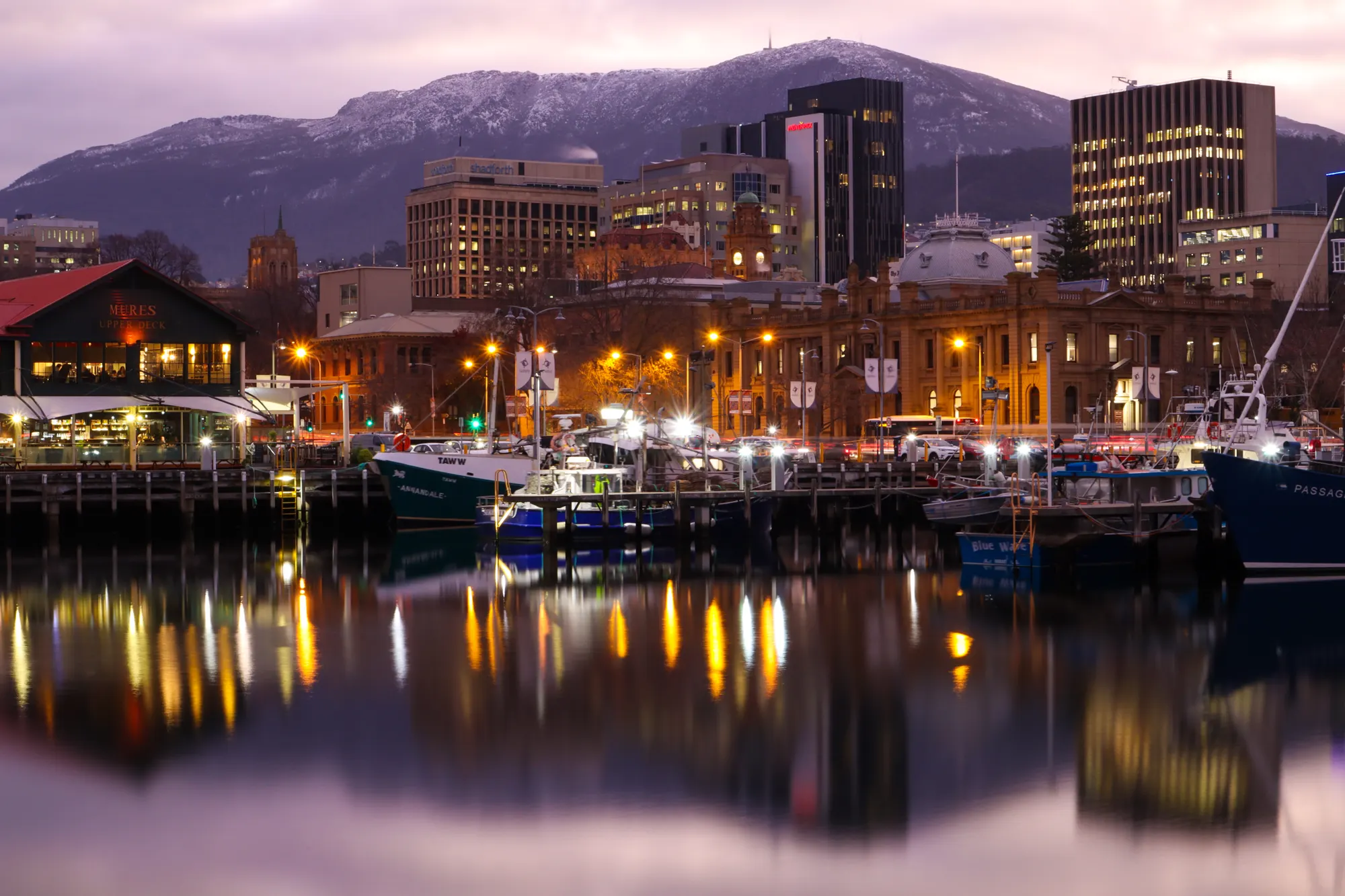 Hobart waterfront at dusk with golden lights reflecting on the water